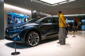 A man examines a blue SUV displayed in a showroom