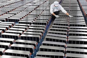 A worker checking battery packs in a warehouse setting