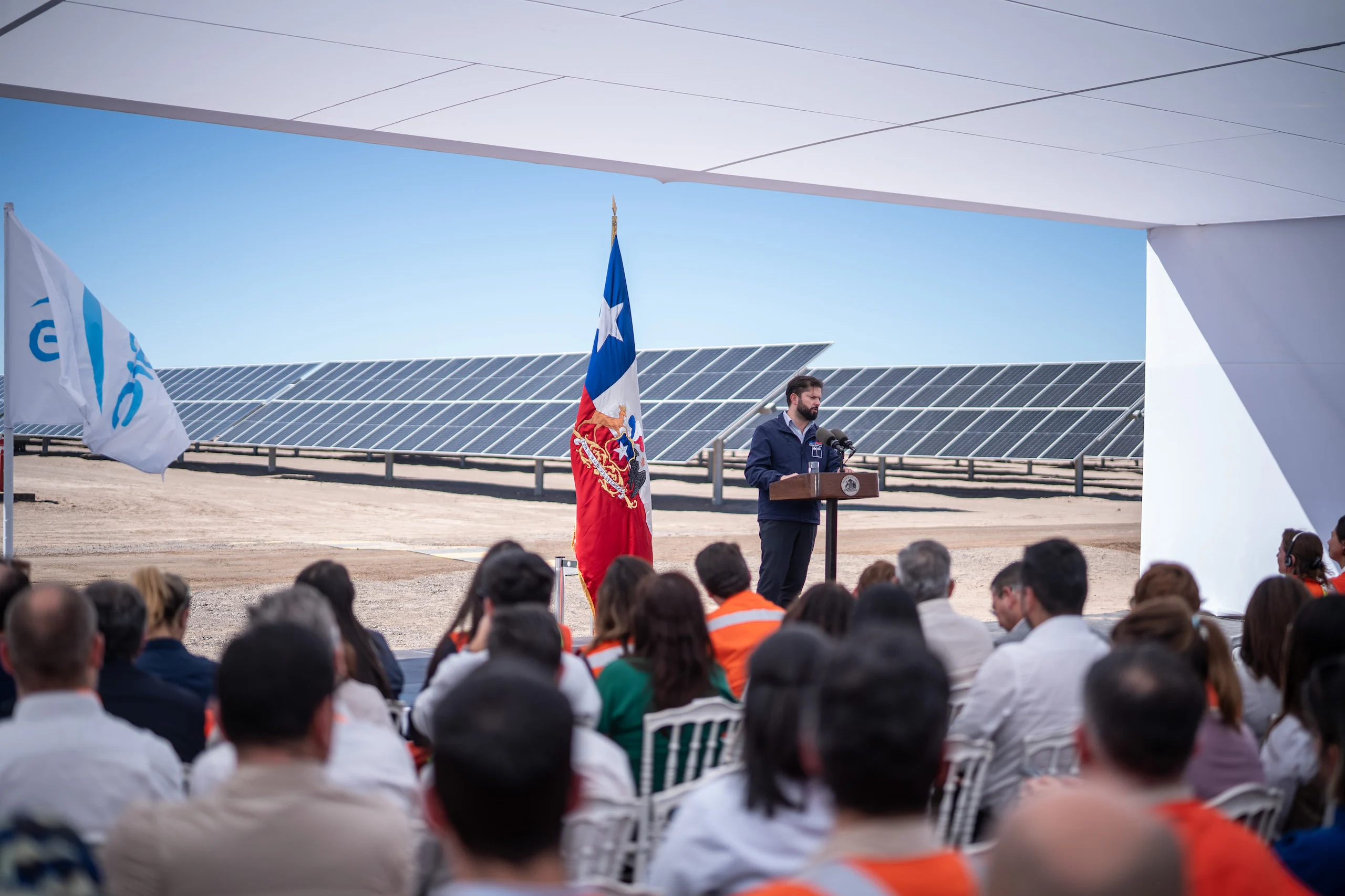 Un hombre vestido con un traje se dirige al público en una planta de energía solar