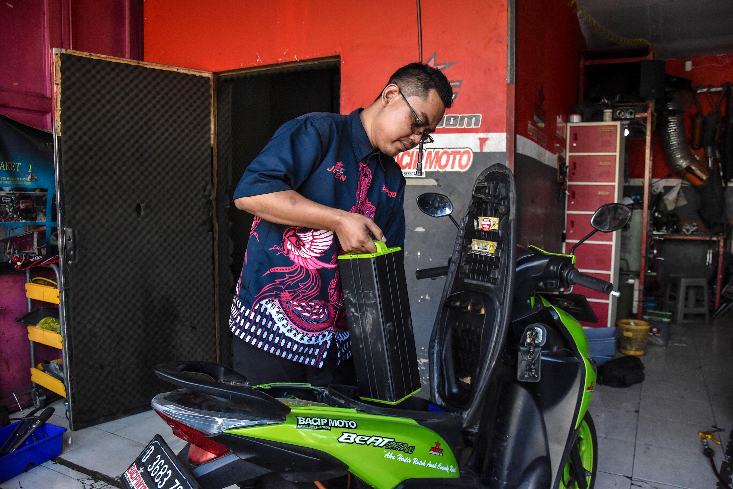 <p>A mechanic in the Indonesian city of Bandung, West Java, replaces the battery of an electric moped (Image: Dimas Rachmatsyah / Alamy)</p>