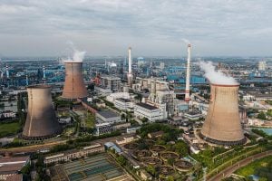 Aerial view of a power plant with smoke billowing from its chimneys