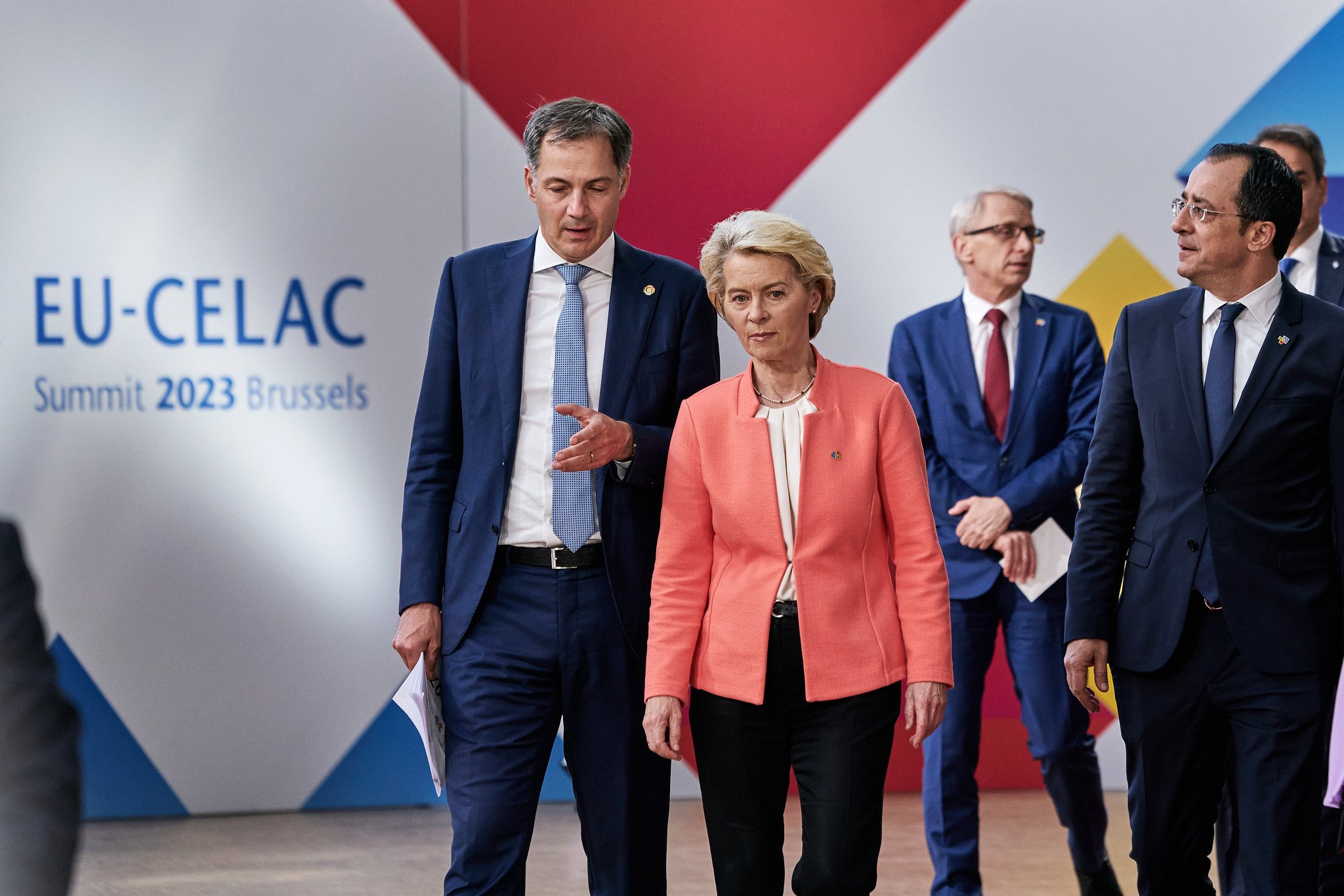 Ursula von der Leyen, com paletó rosa e calça preta, caminha ao lado de dois homens na Cúpula Celac-EU