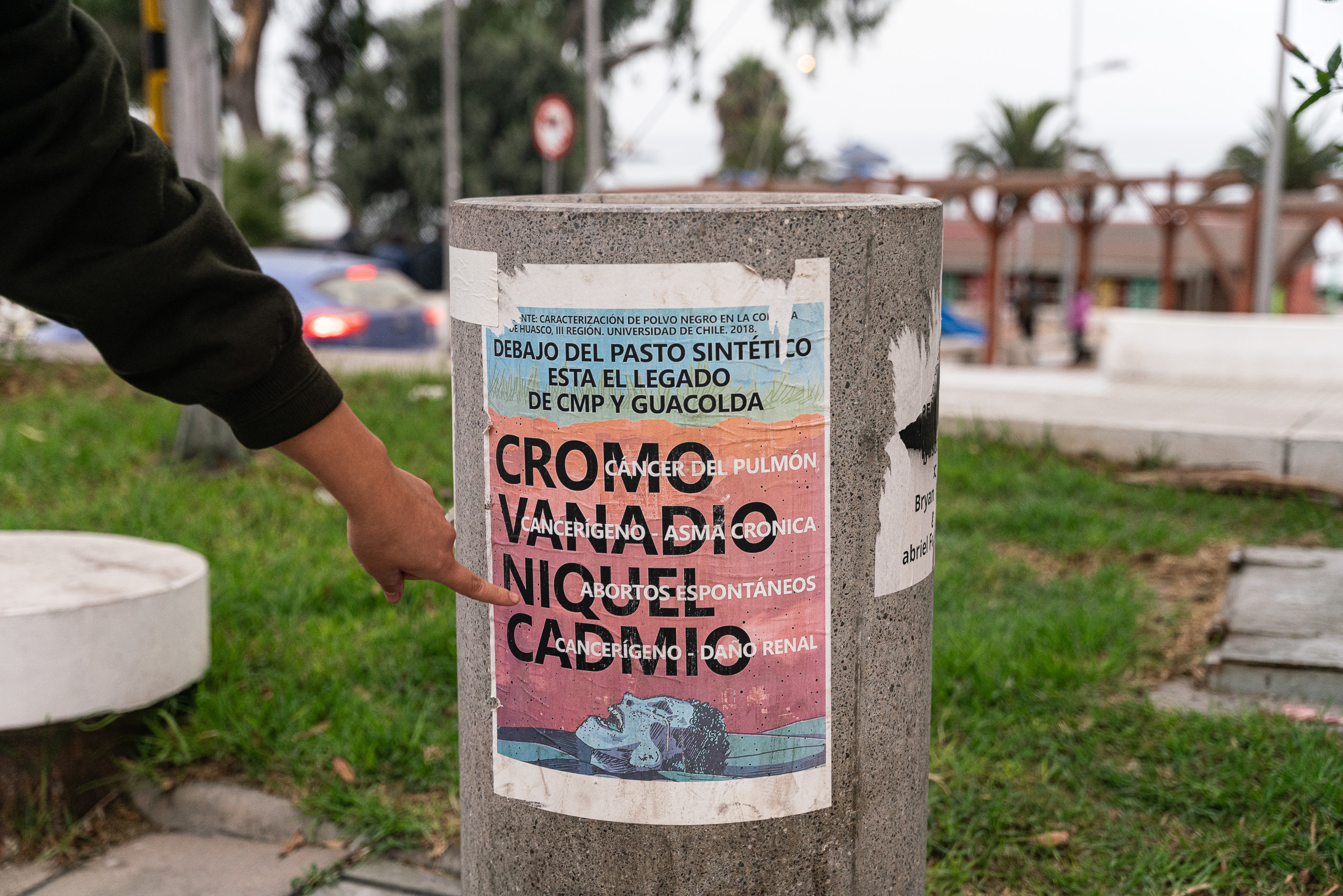 person pointing at poster stuck on concrete slab