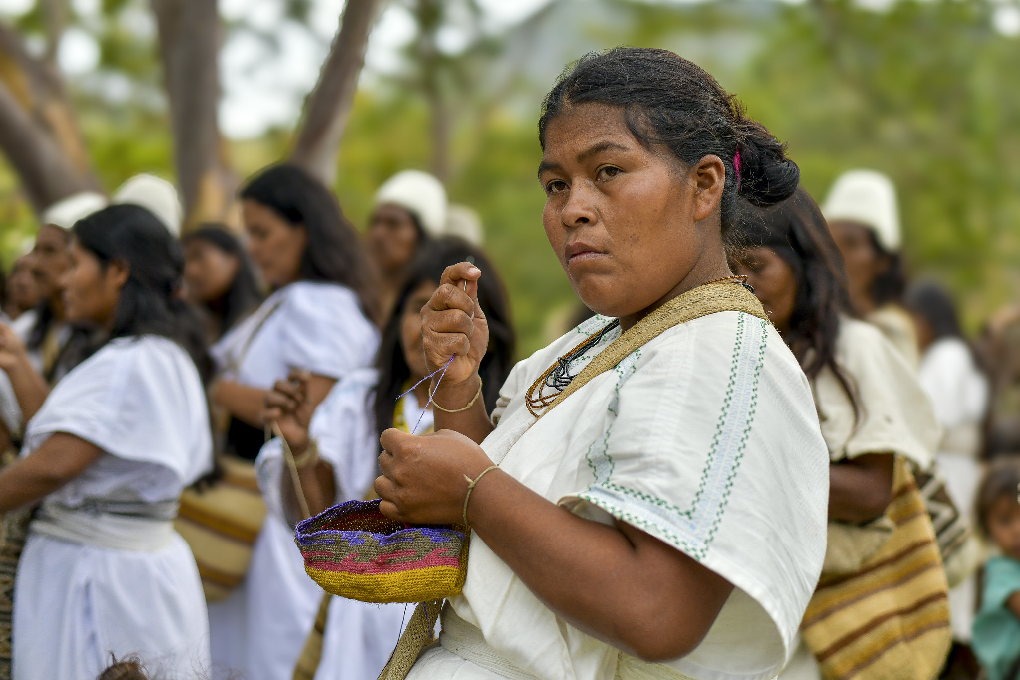 Una mujer haciendo una artesanía entre un grupo de mujeres indígenas arhuaco 