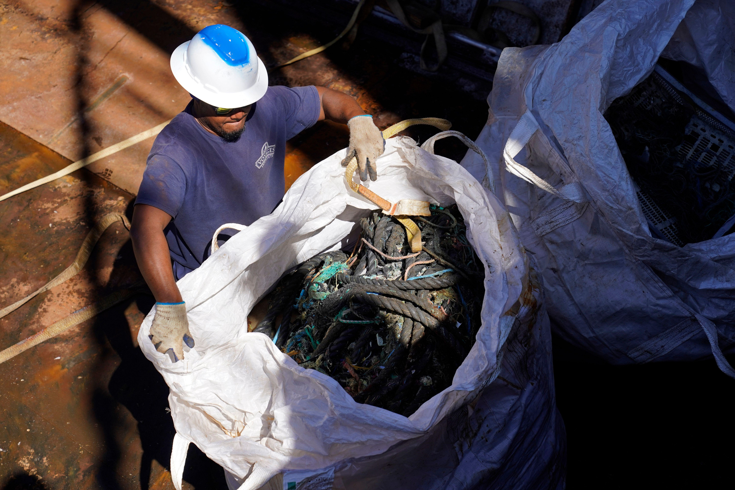 man holding open sack of marine debris