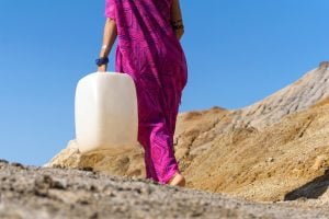 girl carrying a plastic jerrican