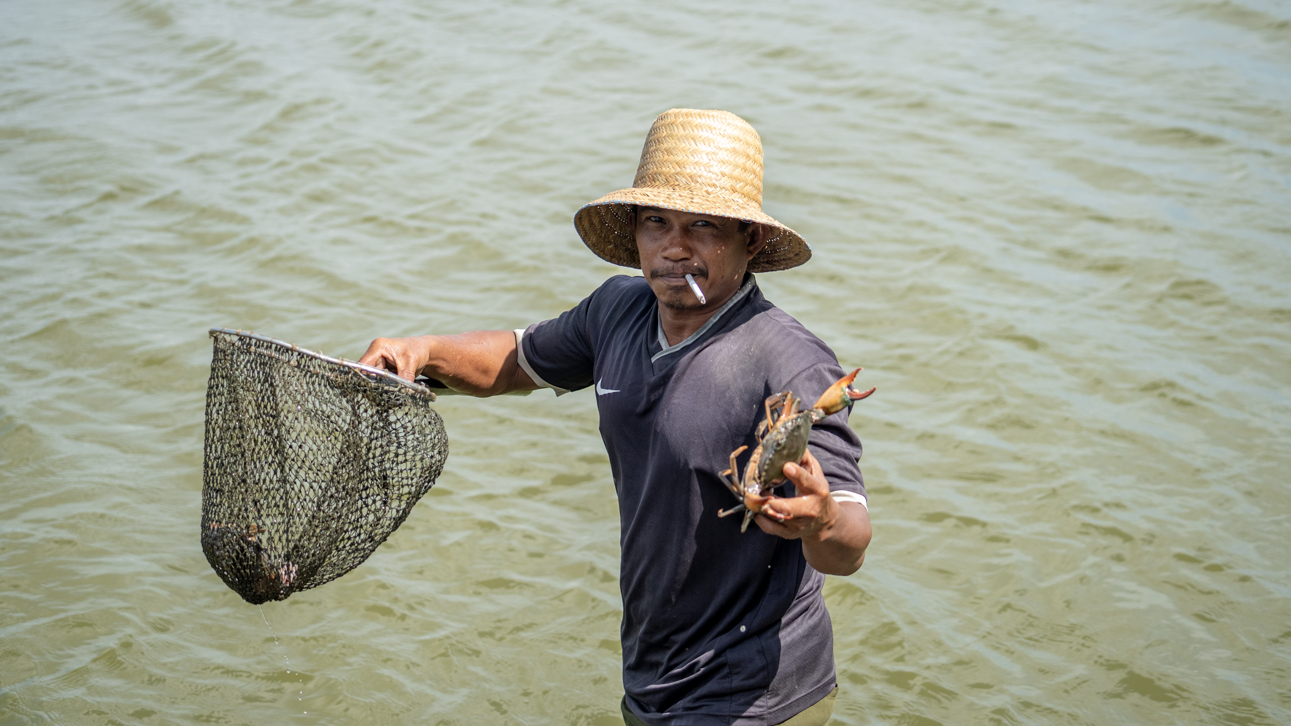 A man holds a crab on his hand and a net on the other hand 