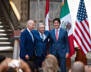 Joe Biden, AMLO y Justin Trudeau, vestidos de traje, con banderas de Canadá, México y EE.UU detrás