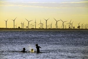 Children playing in the sea with wind farm in distance