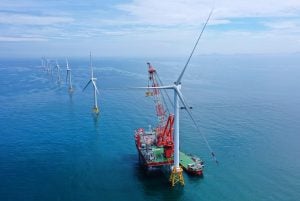 Several wind turbines stand in the ocean