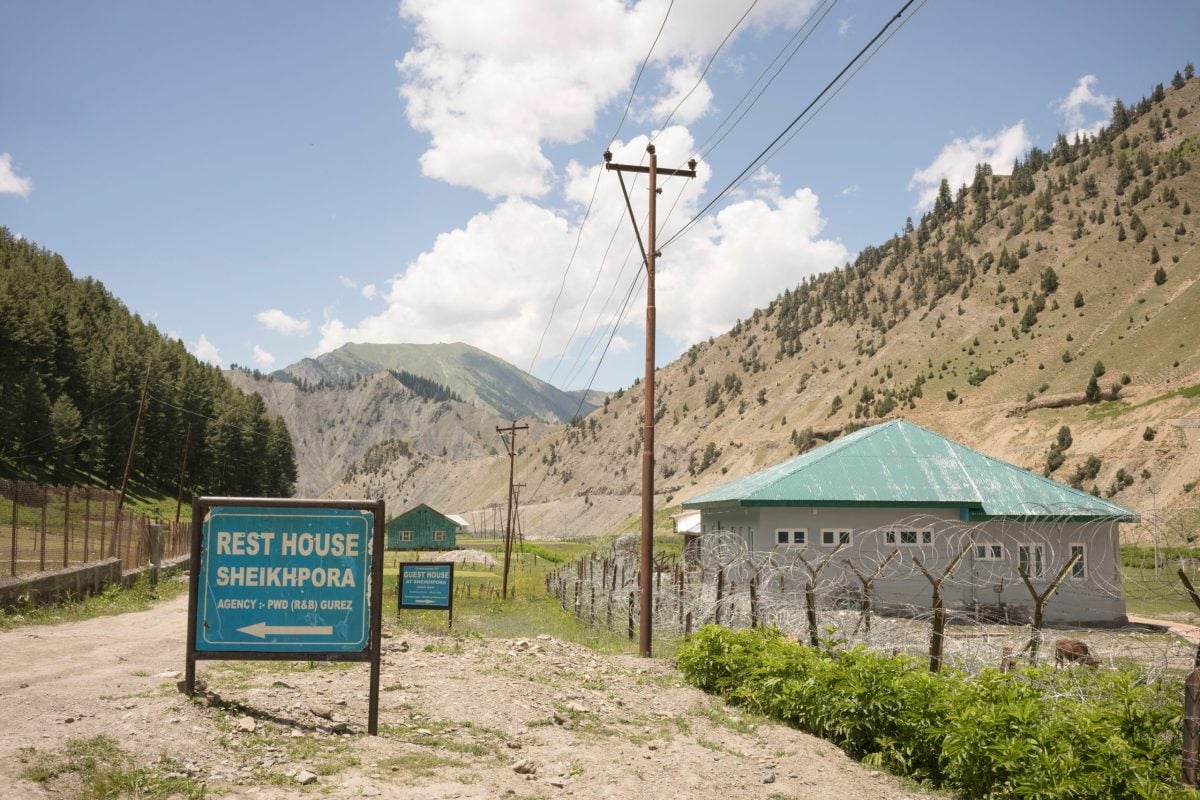 sign near low wire fence with concrete buildings in background