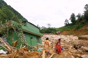 Women collect their belongings from their destroyed homes after the floods