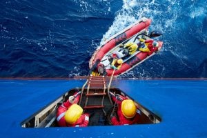 Inflatable raft on water below ship