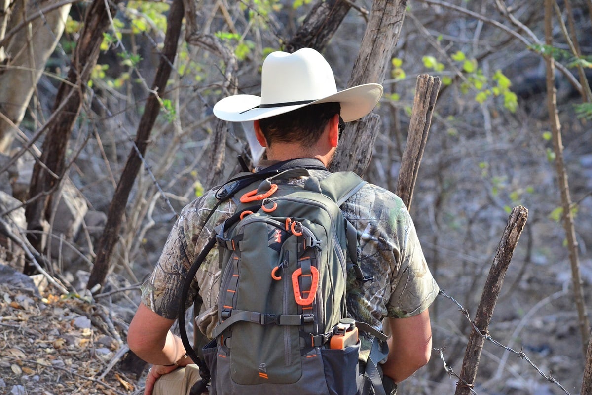 Un hombre con una mochila de senderismo en su espalda y un sombrero blanco al aire libre