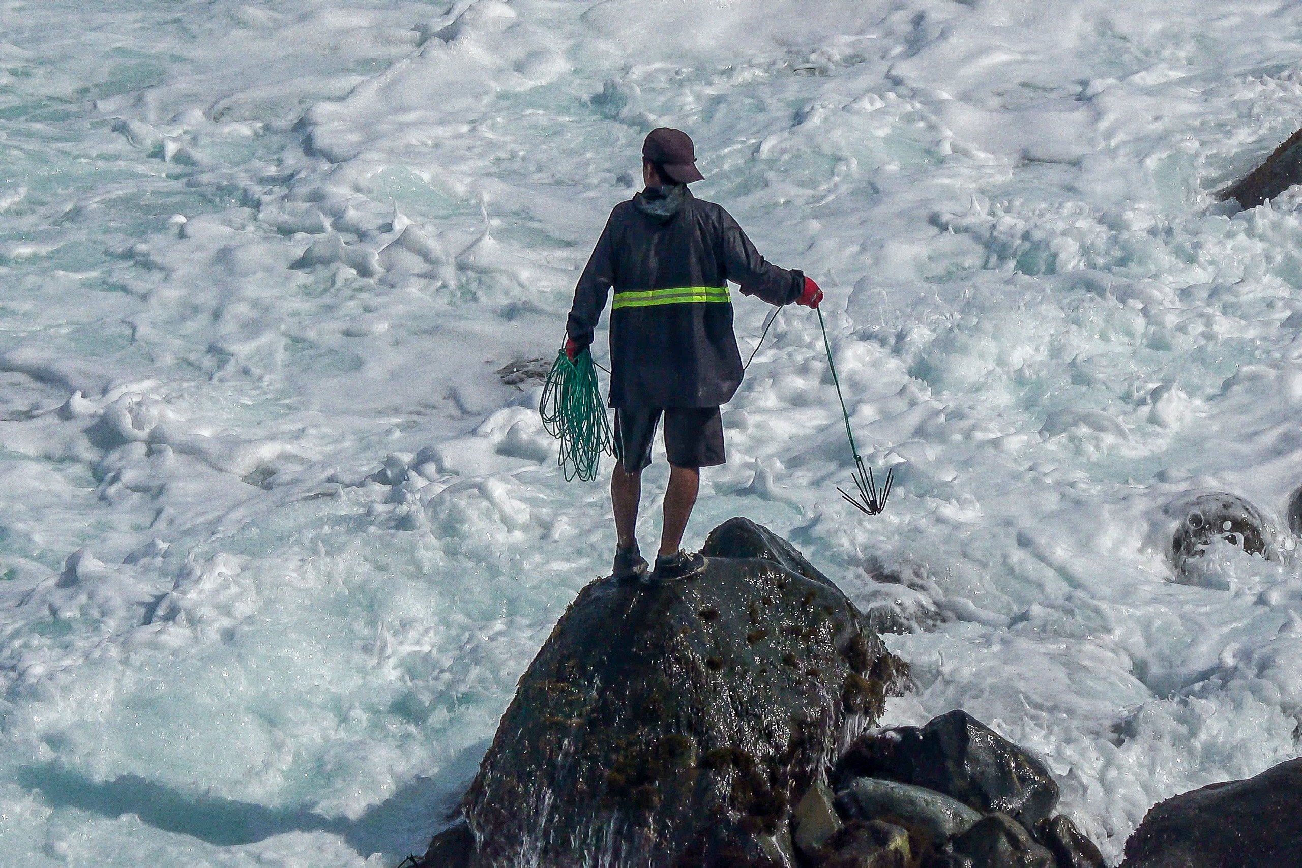 una persona parada sobre una roca en la orilla del mar