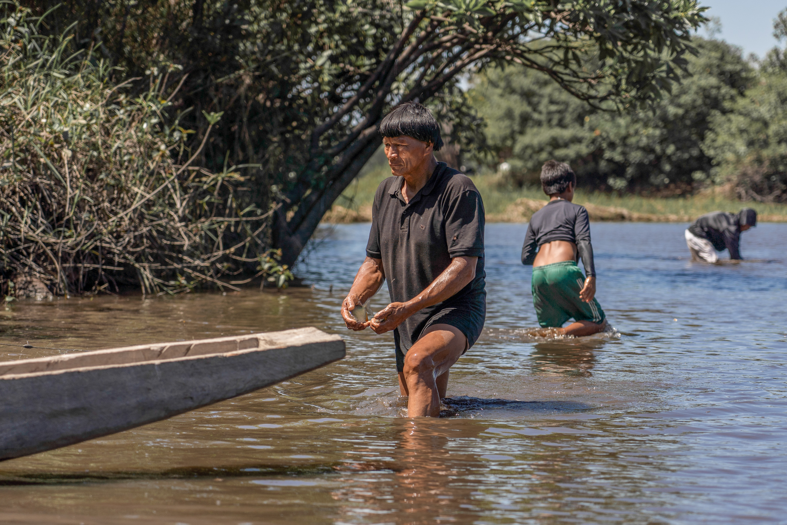 Un hombre en una laguna con un pescado en sus manos