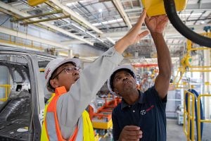 Two men collaborating on a vehicle assembly line