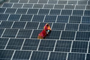 girls standing between rows of solar panels