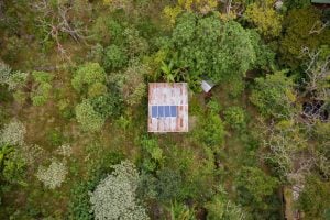 aerial view of solar panels on roof in forested area