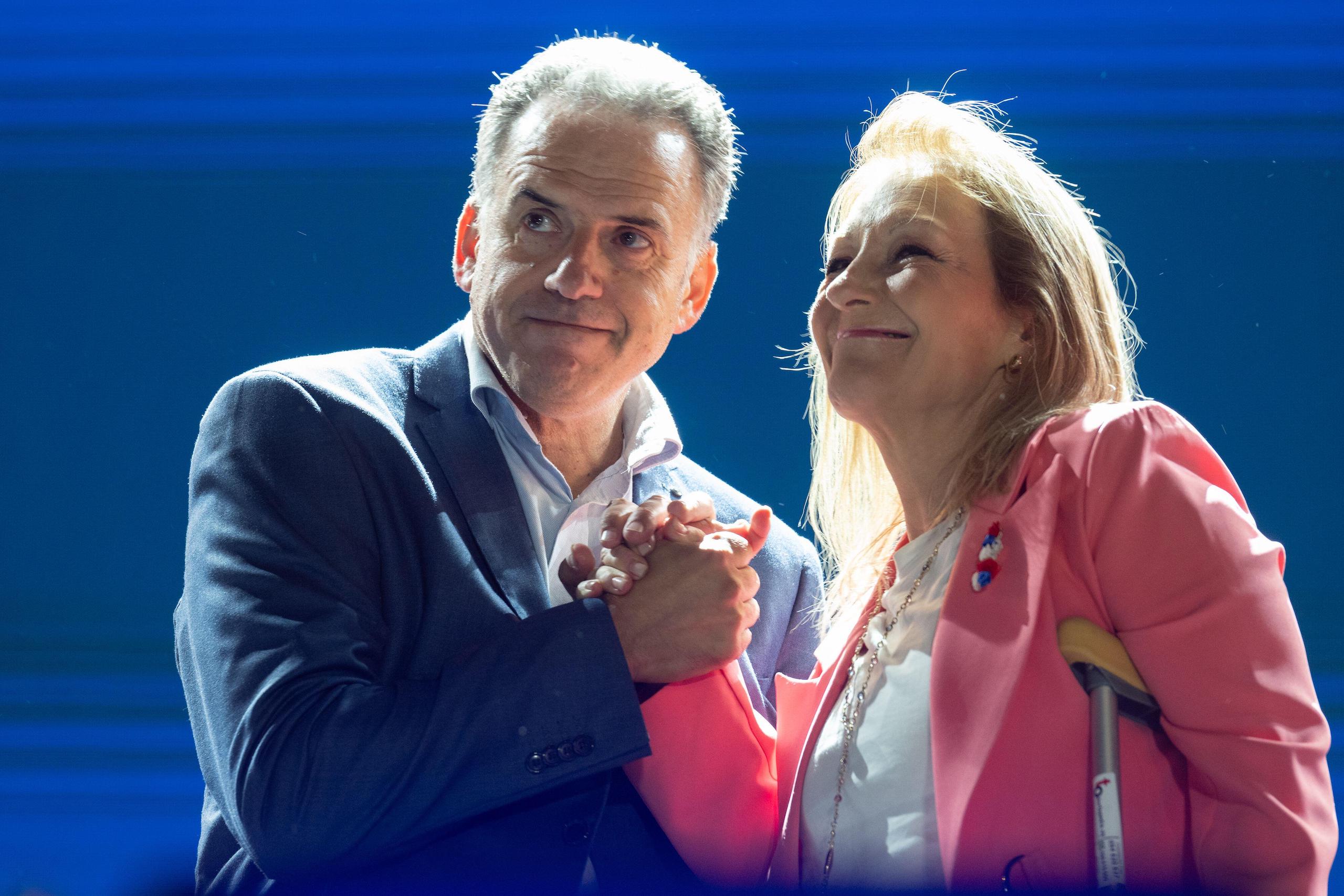 A man and woman stand side by side holding hands