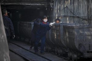 Workers push mine cars at a coal mine