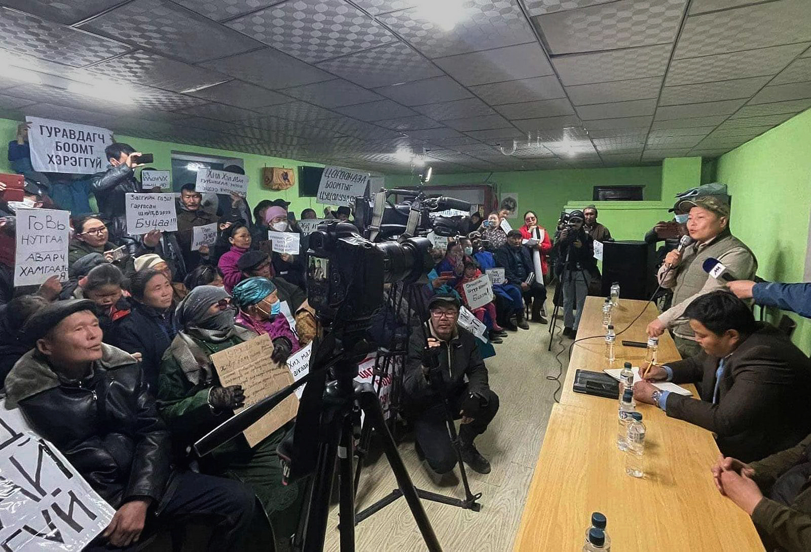 crowd of people holding signs indoors