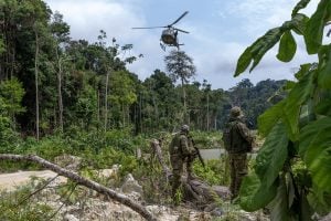 Un helicóptero sobrevuela un bosque, con soldados apostados debajo