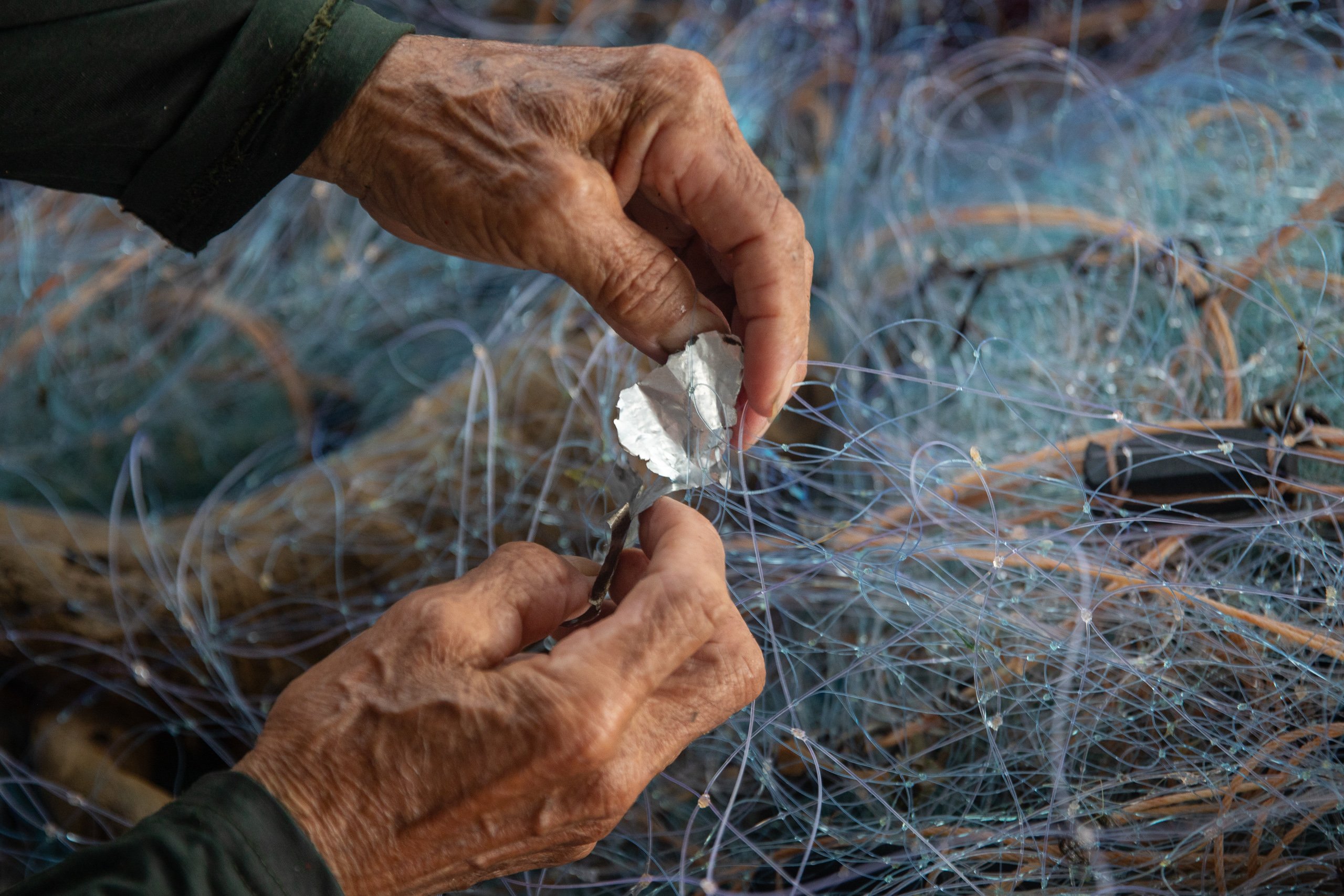 A man picks up a small piece of plastic from the fishing nets