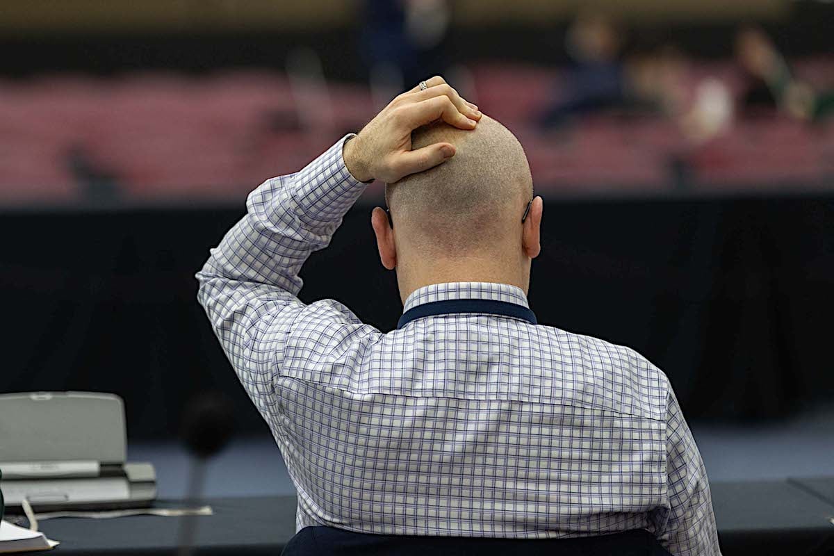 A man at a table has his hands on his head