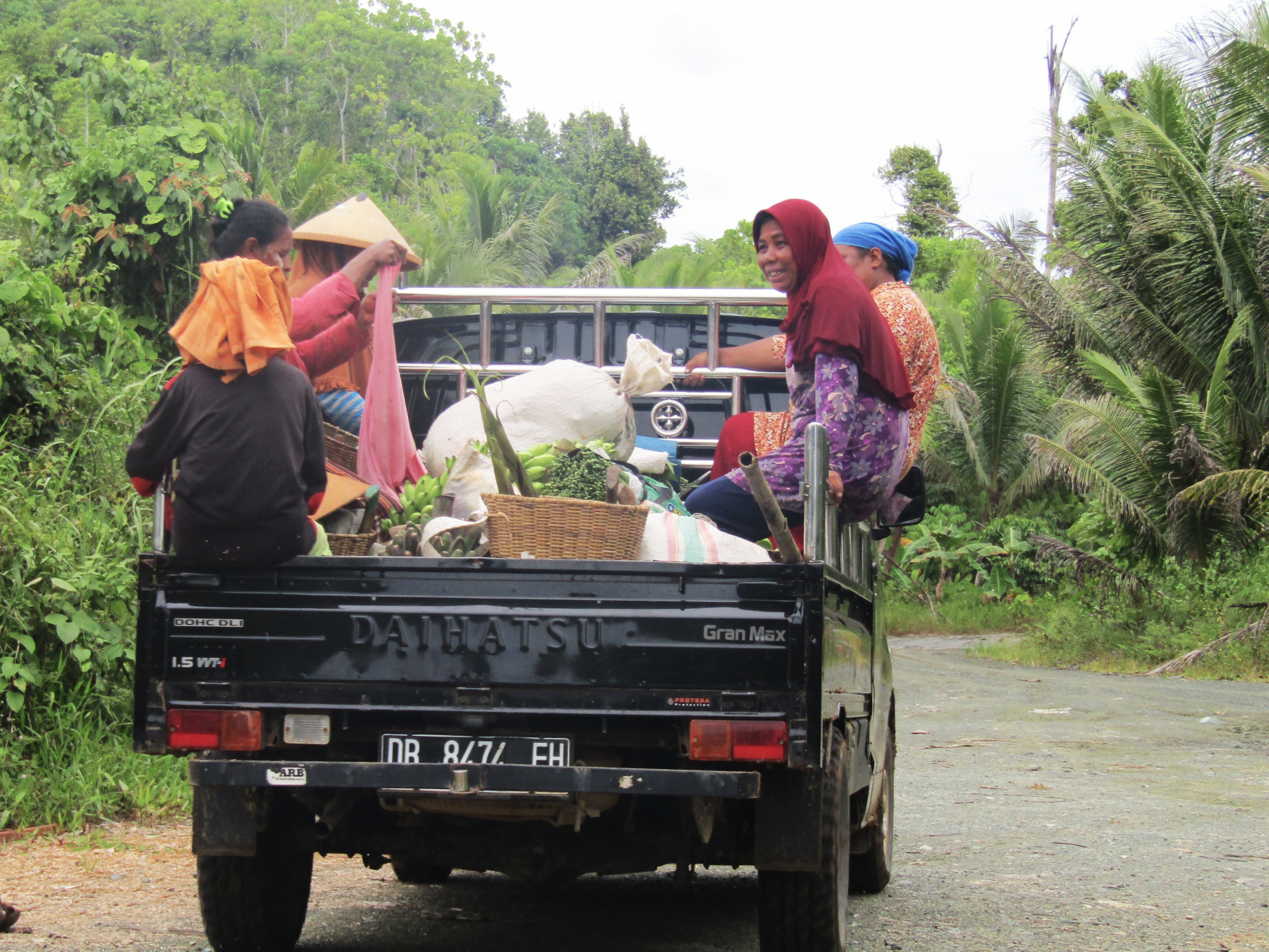 A black truck carrying several people in the back