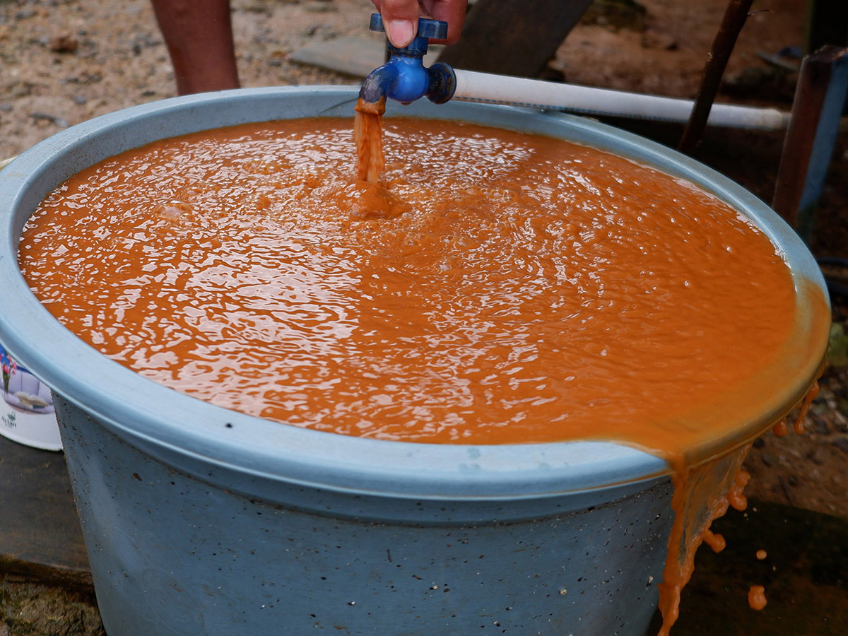 orange liquid running from a container into a large bucket