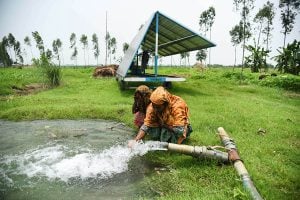 two women draws water from a solar-powered pumps