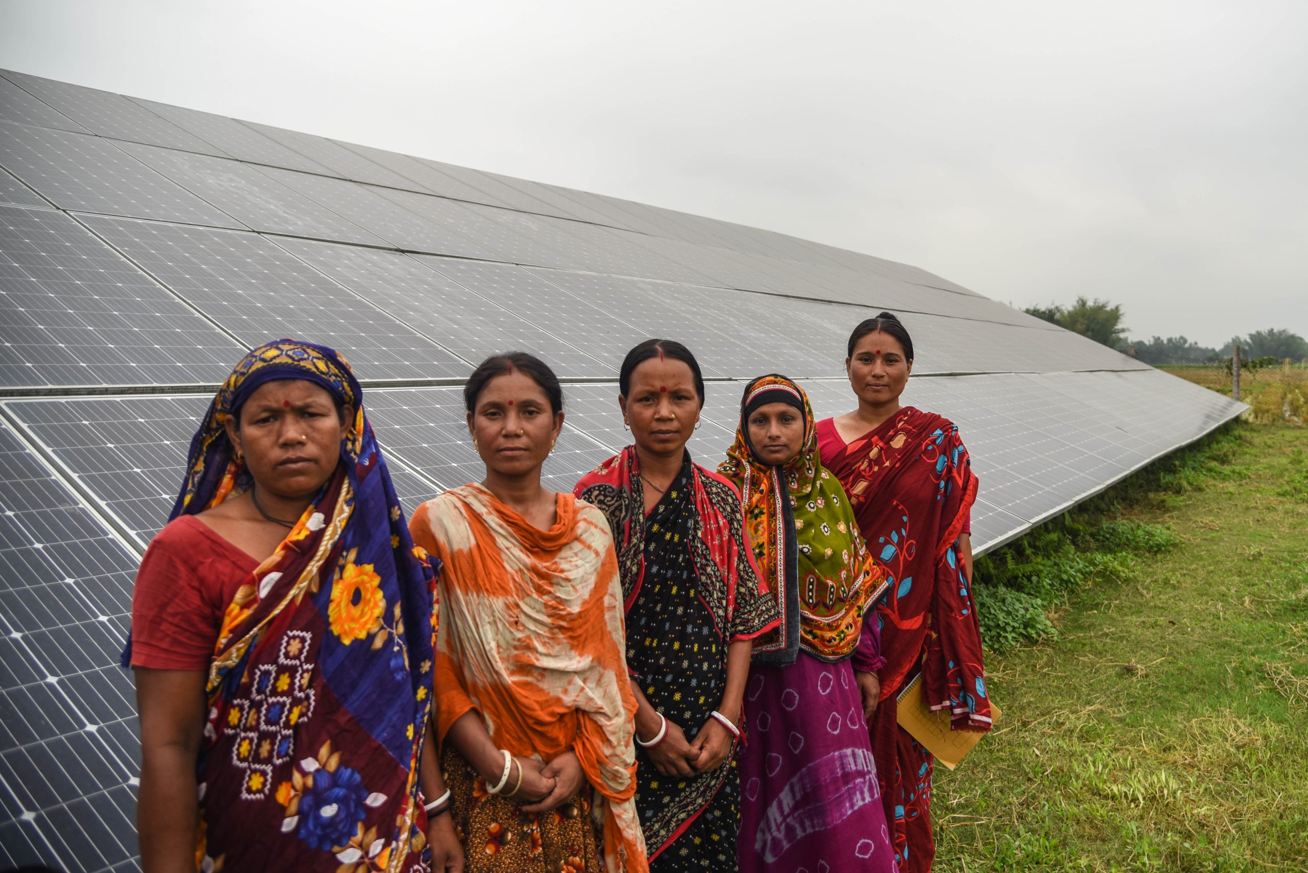 Women stand in front of solar panels