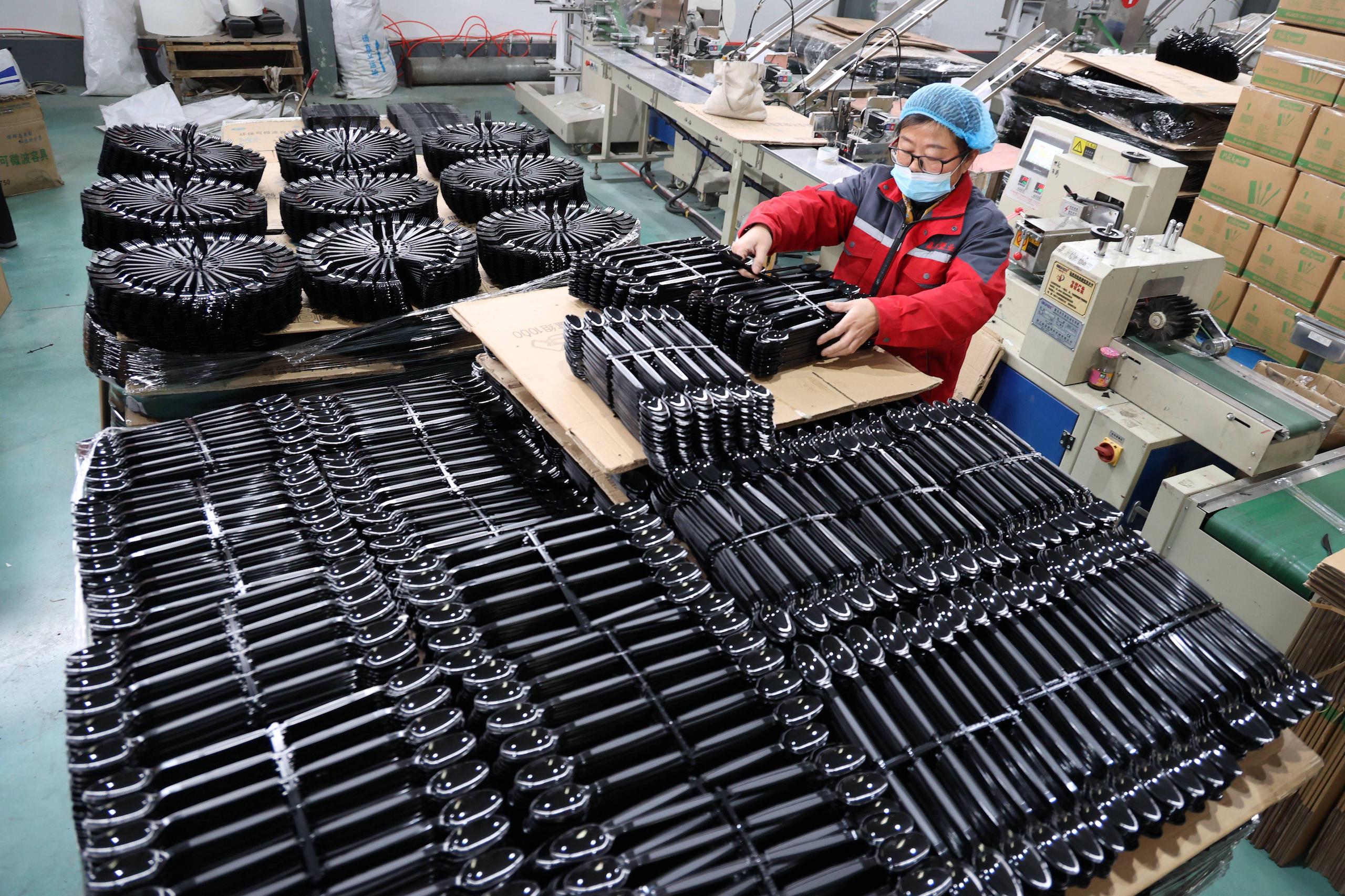 A factory worker is engaged in the production of black plastic boxes
