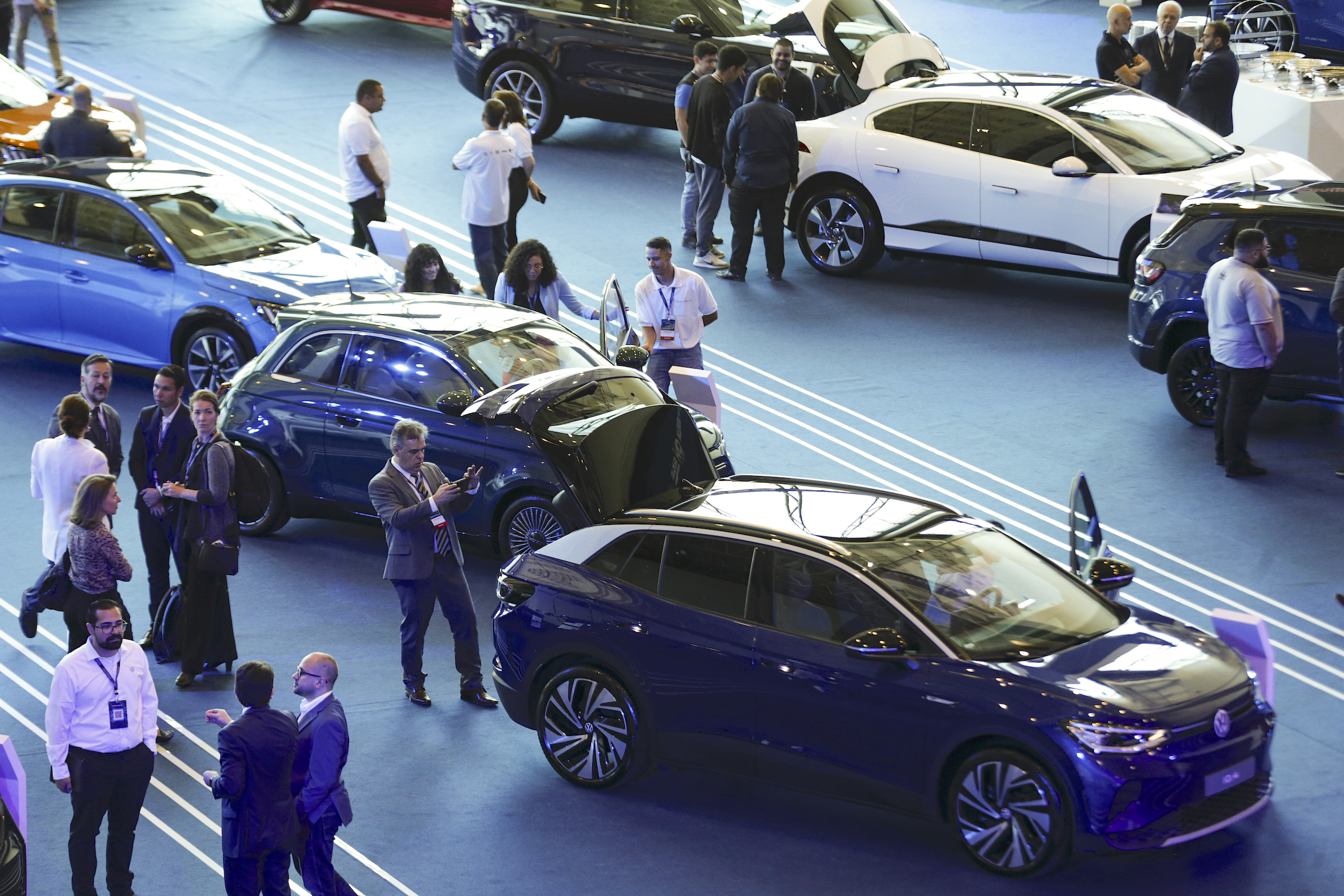 A crowd of people surrounds an array of cars at a car show