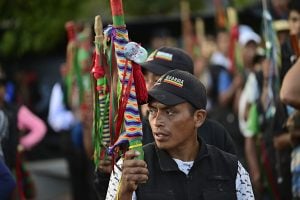 A man holds a vibrant flag on a stick