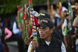 Un hombre sostiene una bandera de colores vibrantes en un palo