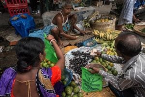 people are purchasing fresh fruits and vegetables at a street market