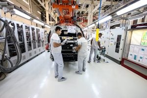 Two men collaborating on a car assembly line