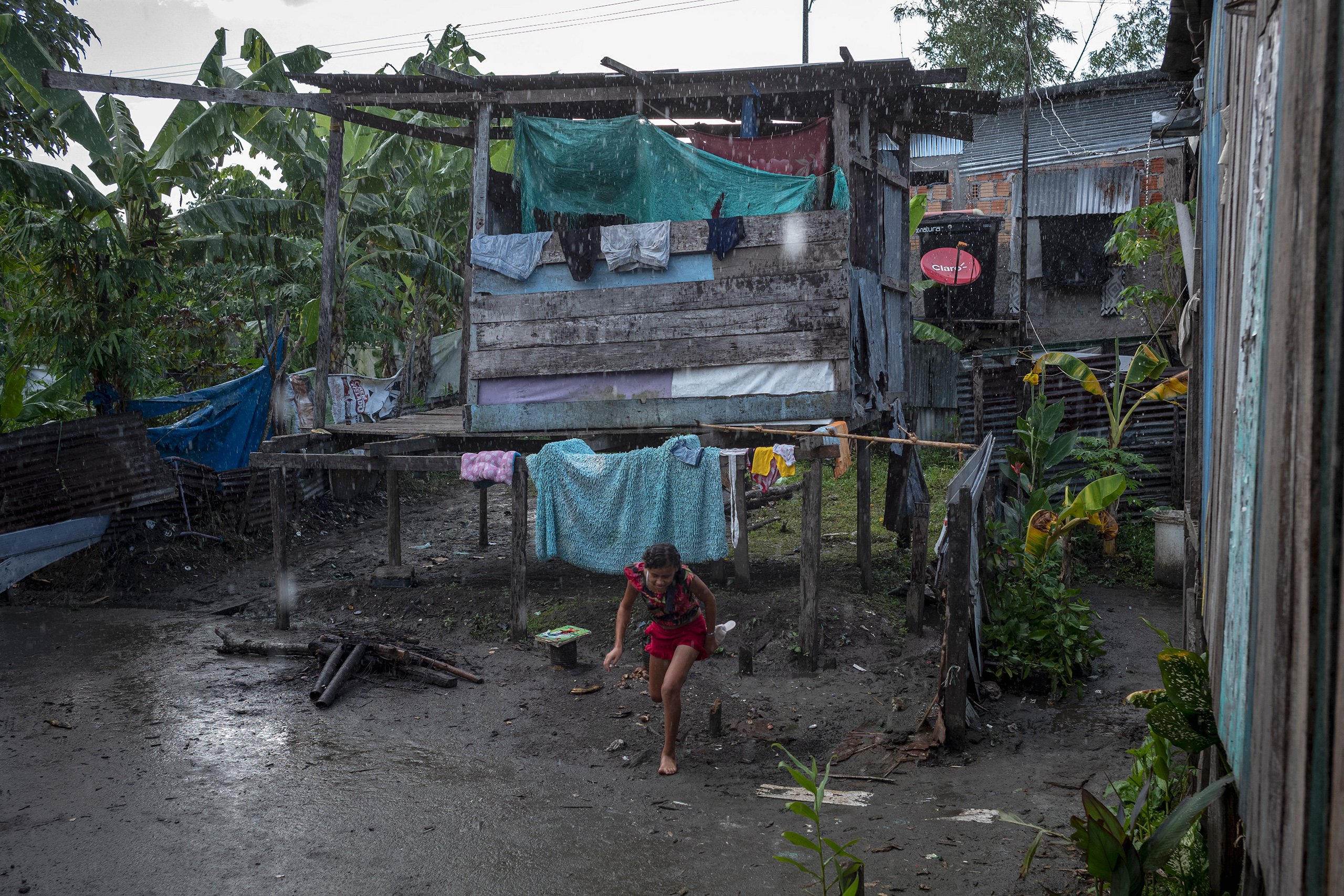 girl hunched over in rain near wooden structure