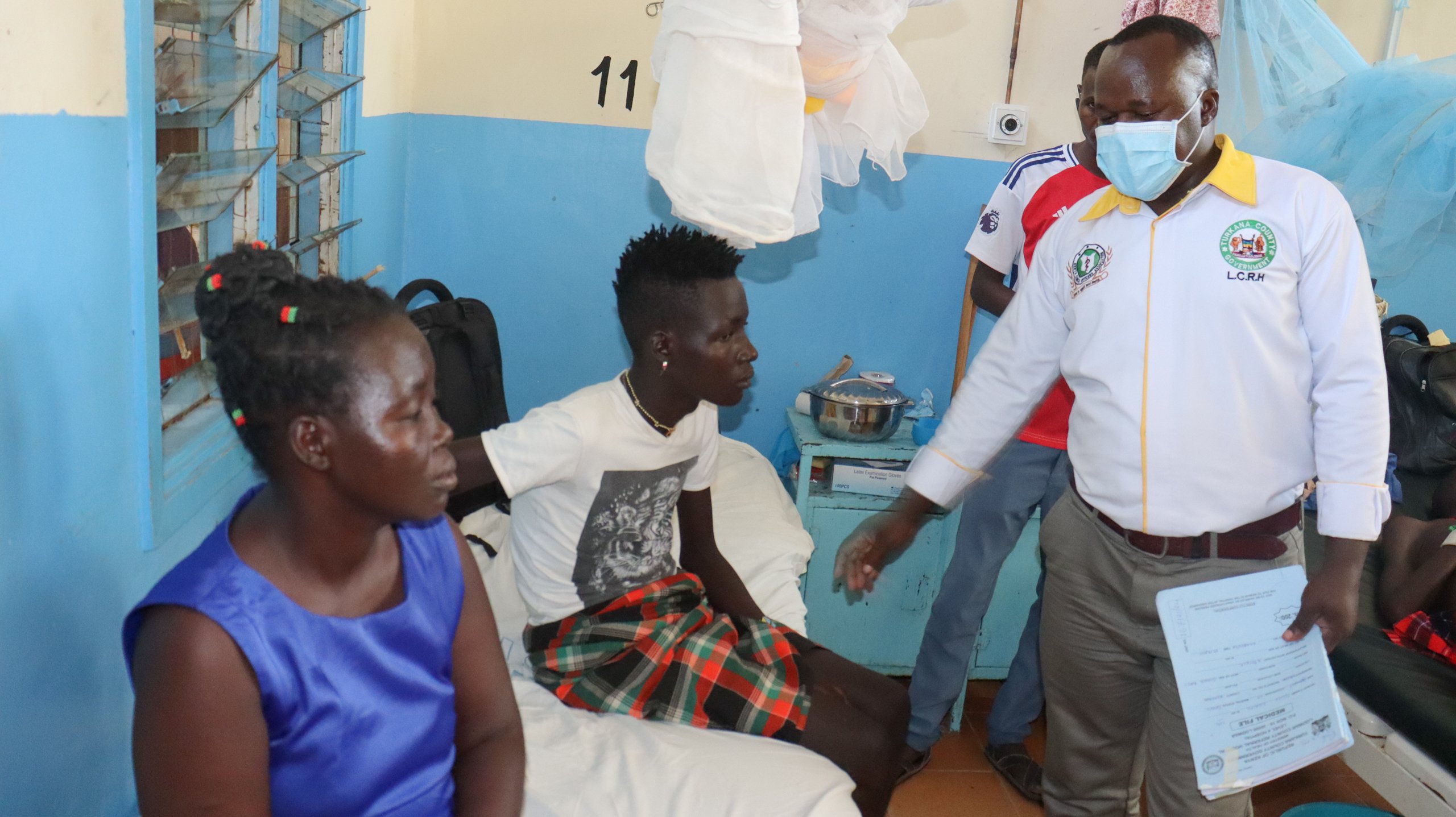 <p>Leishmaniasis patient Ekidor Kiyong is attended to by Dr Kennedy Wasilwa at the Lodwar County Referral Hospital, Turkana, Kenya. His aunt Ester Loskiria sits beside him (Image: Scovian Lillian)</p>