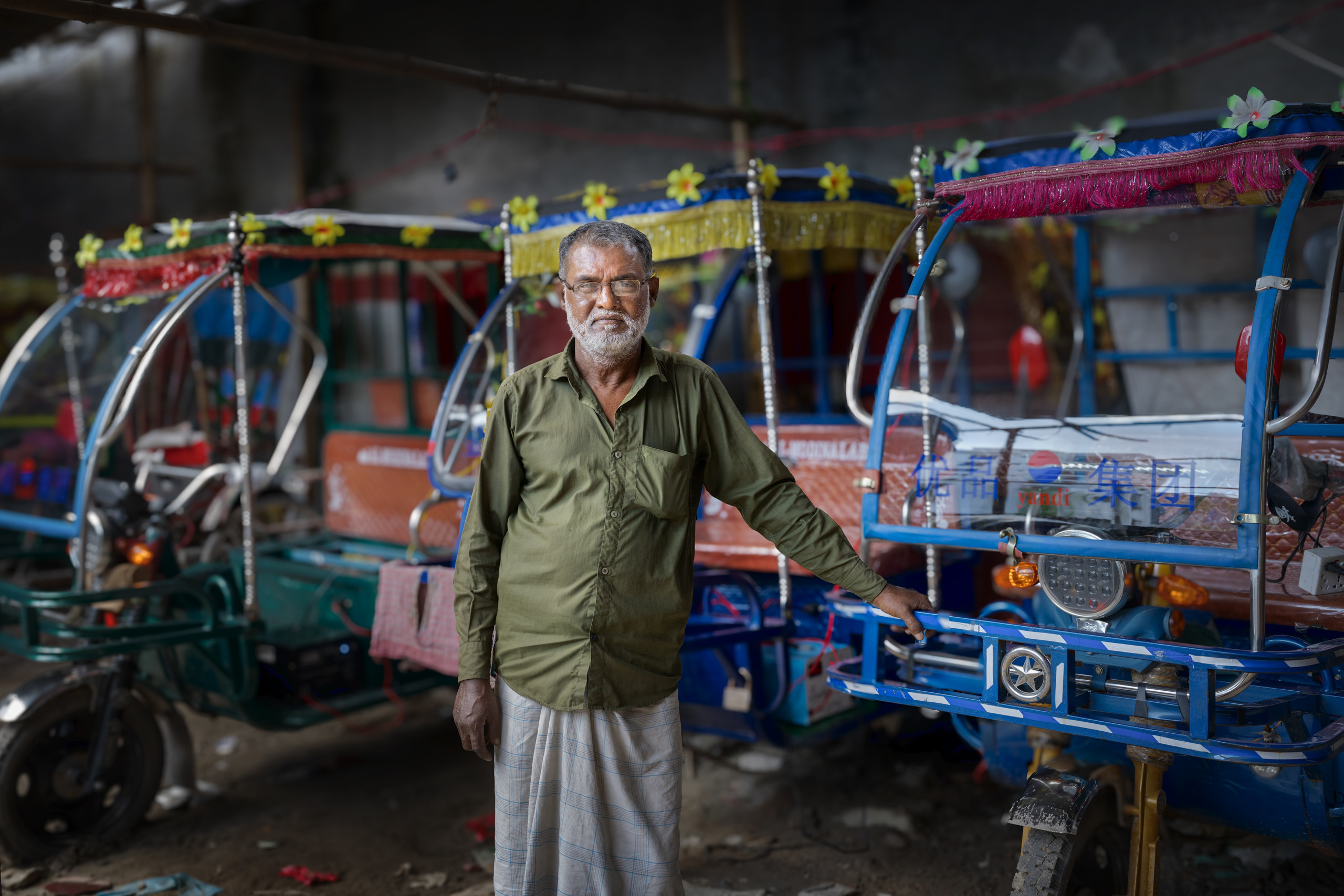 man standing in front of row of rickshaws