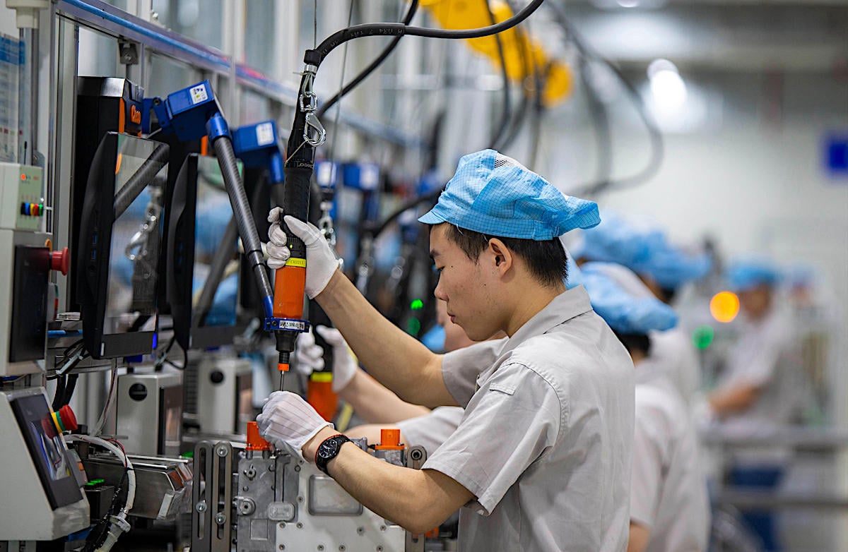 A factory worker operates a machine at a production line