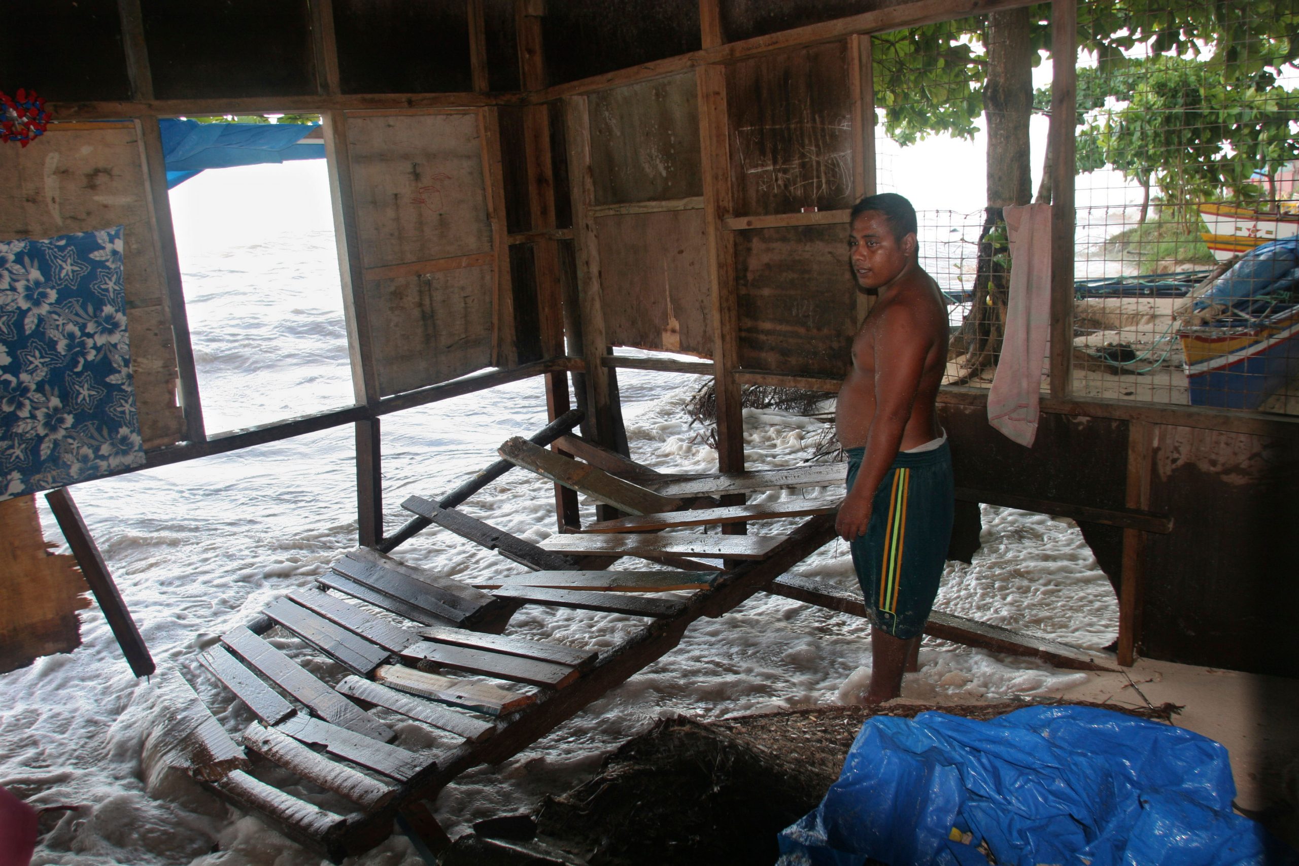 man standing in coastal house with washed away floor