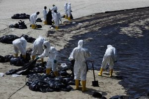 people in white suits on oil covered beach