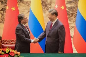 Gustavo Petro and Xi Jinping shaking hands in front of Chinese and Colombian flags