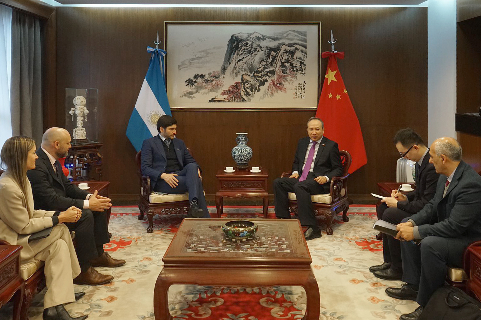 Seis personas sentadas en semicírculo, con las banderas de China y Argentina