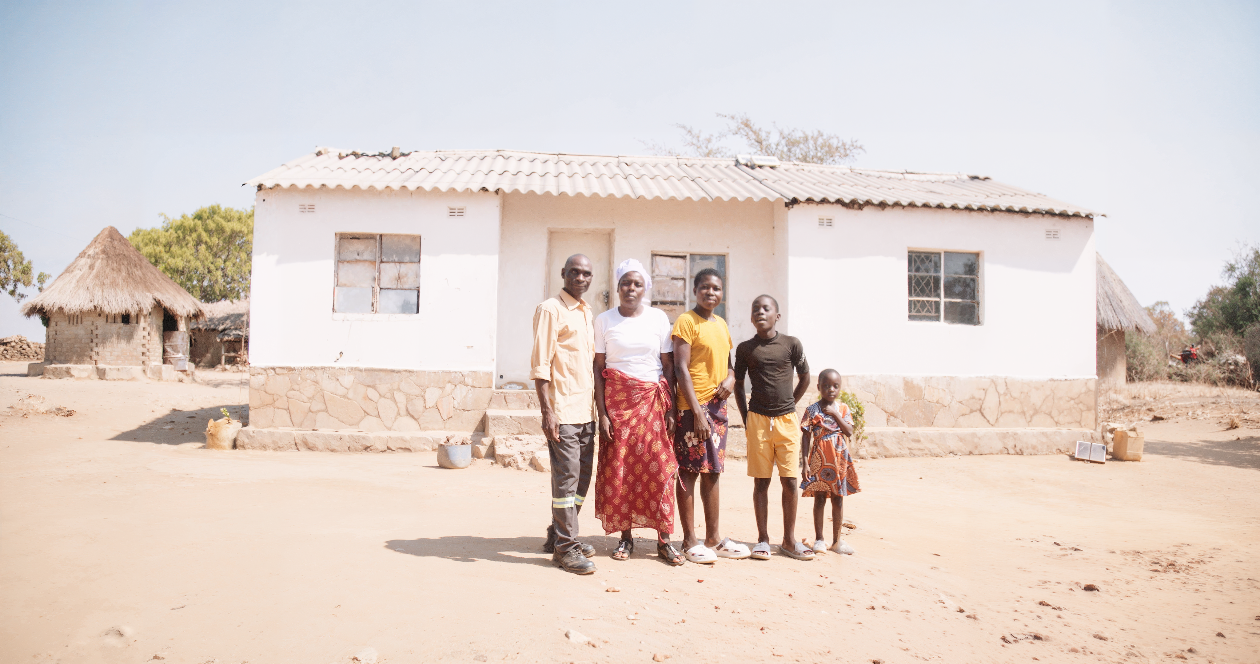 five people stand in front of a house