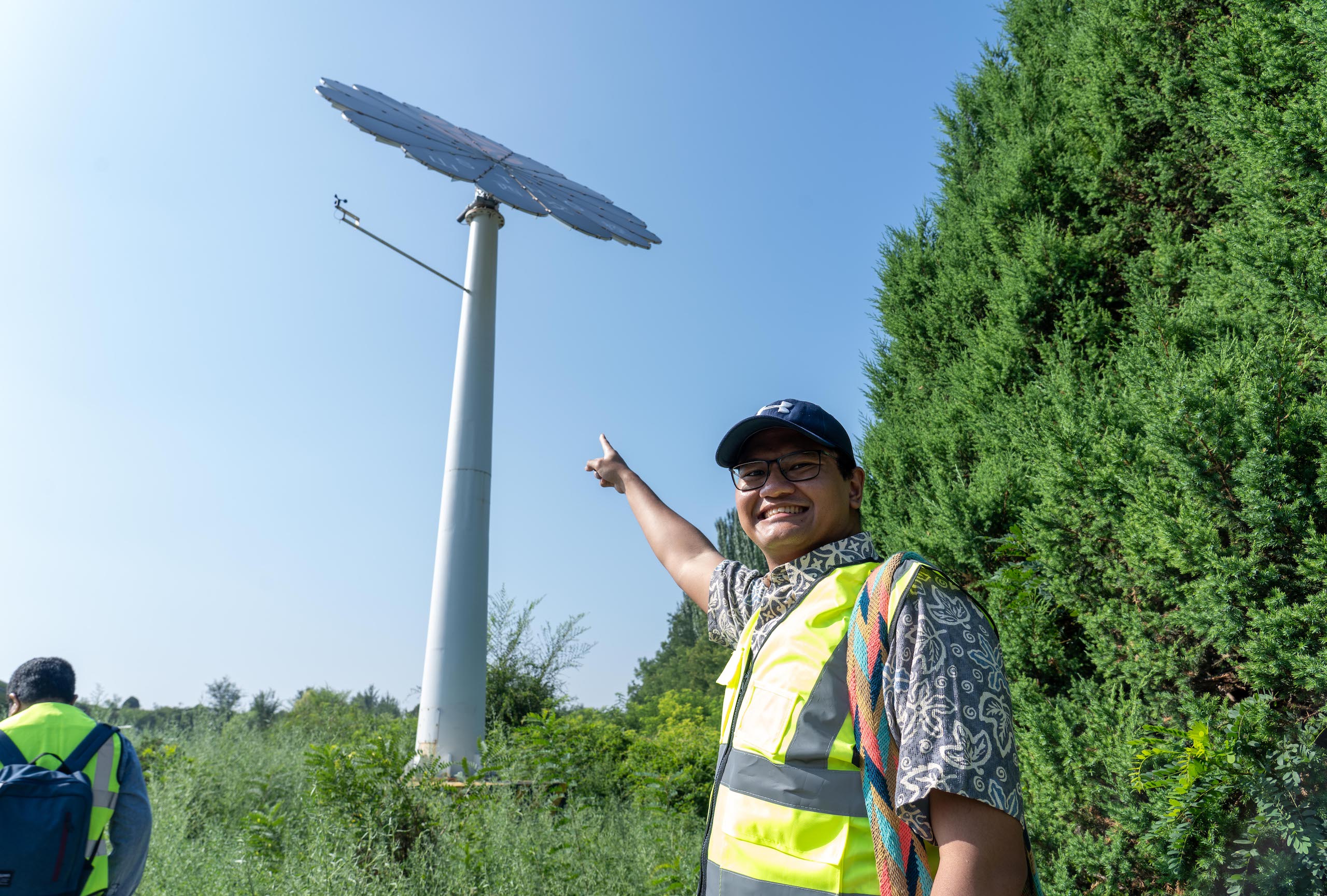 A man wearing a safety vest points at a solar panel