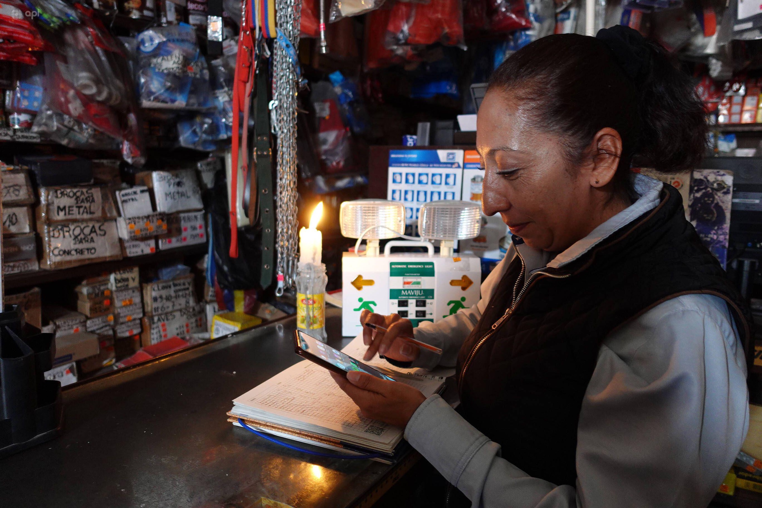 a woman uses her phone by candlelight in a shop